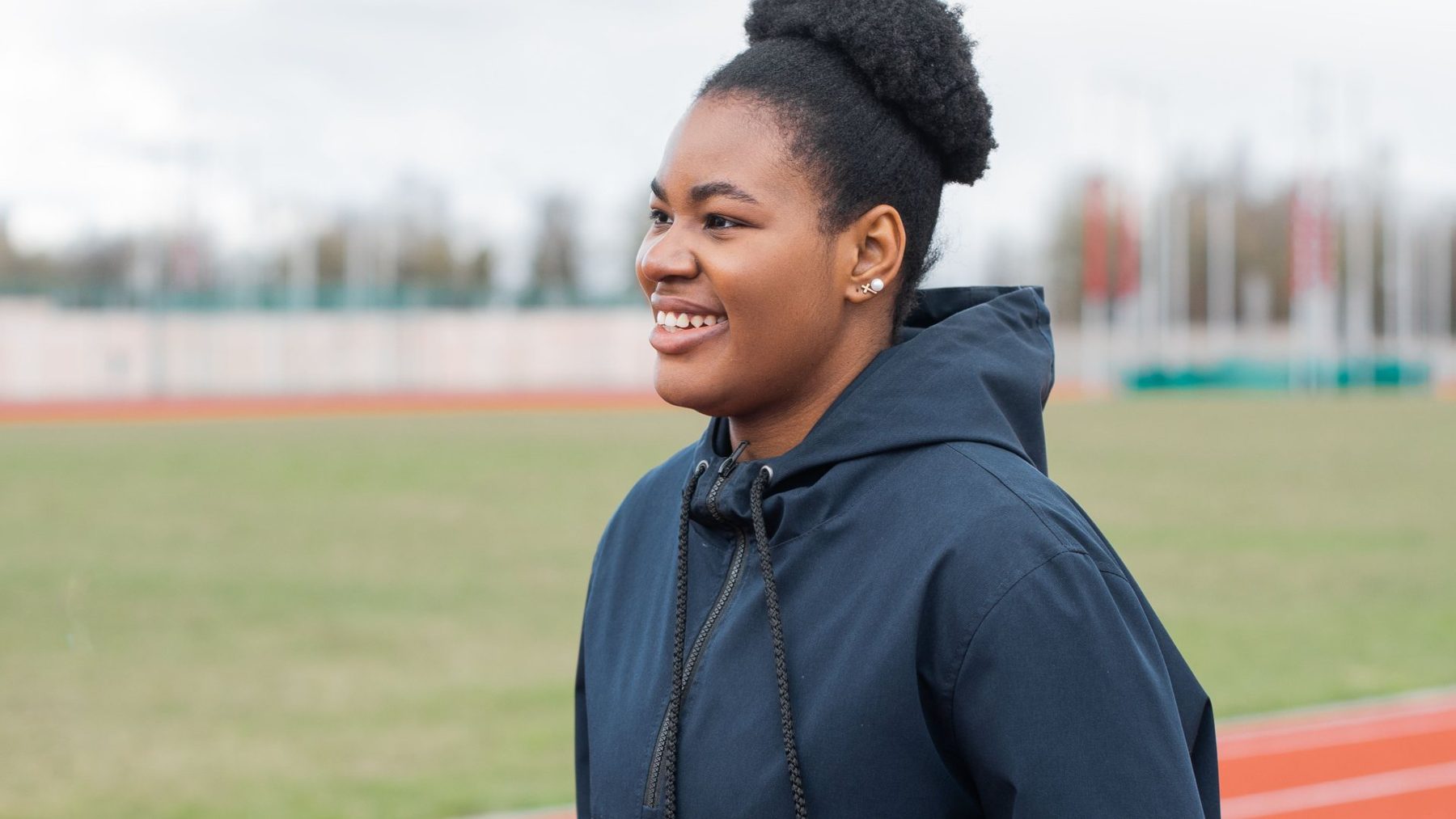 A track athlete smiling at the field